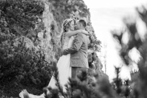 Hochzeit Bergshooting Christina und Michael - Schwarz-weiß Aufnahme - Brautpaar steht auf einem Berg in der Natur und küsst sich