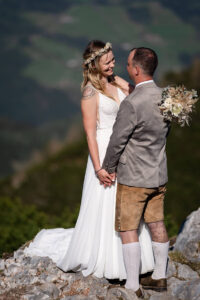 Hochzeit Bergshooting Christina und Michael - Brautpaar steht auf einem Berg in der Natur und schaut sich verliebt in die Augen