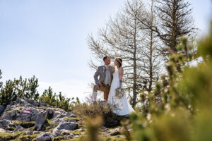 Hochzeit Bergshooting Christina und Michael - Brautpaar steht auf einem Berg in der Natur - Bräutigam und Braut schauen sich in die Augen