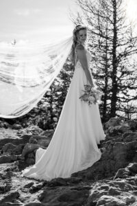 Hochzeit Bergshooting Christina und Michael - schwarz-weiß Aufnahme - Braut steht auf einem Berg, der Wind bläst durch ihren Schleier