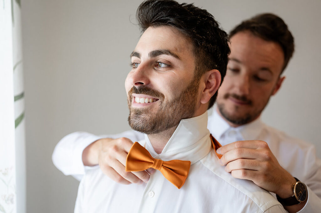 Hochzeit Julia und Stefan - Nahaufnahme Beistand und Bräutigam - Beistand bindet die Fliege von Bräutigam