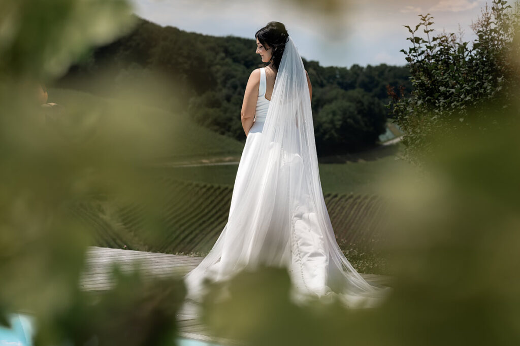 Hochzeit Julia und Stefan - Brautshooting - Braut steht mit dem Rücken zur Kamera und lächelt über ihre Schulter in die Kamera