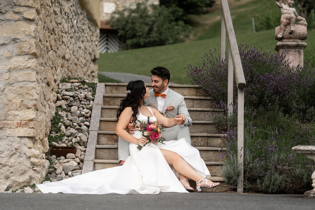 Hochzeit Julia und Stefan - Brautpaar sitzt auf einer Stiege Arm in Arm und lächelt sich an