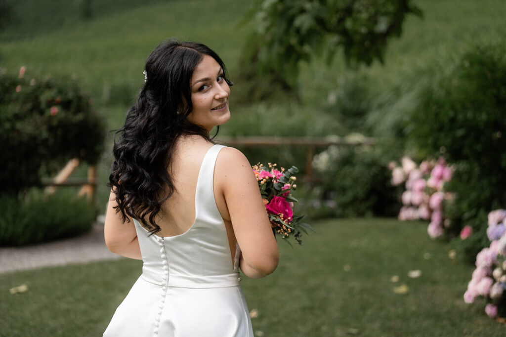 Hochzeit Julia und Stefan - Brautshooting - Braut steht mit dem Rücken zur Kamera und lächelt über ihre Schulter in die Kamera