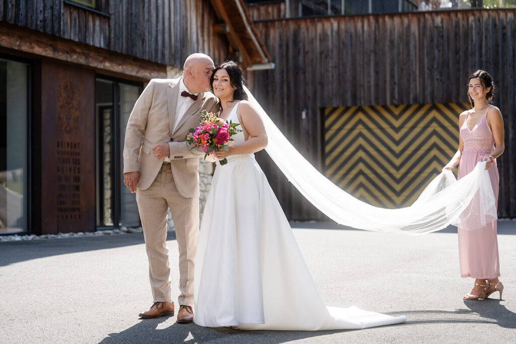 Hochzeit Julia und Stefan - der Brautvater mit seiner Tochter in den Händen und die Brautjungfer hält den Schleier vor der standesamtlichen Trauung