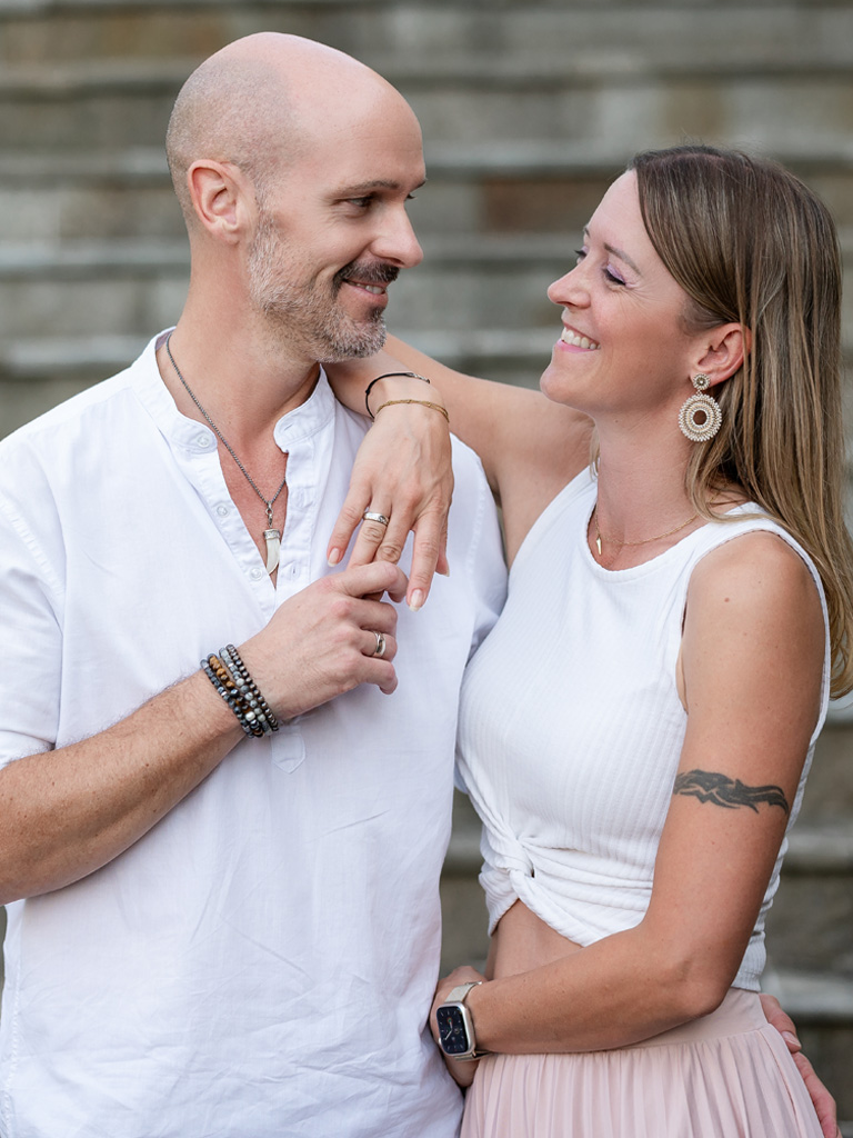 Astrid und Norbert Tschabuschnig - Paarfoto - Fotografin und Fotograf schauen sich in die Augen und lächeln einander an.